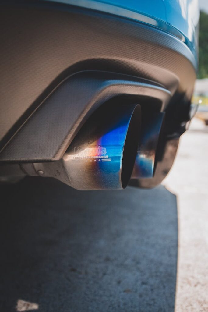 Detailed close-up of a car's exhaust pipes featuring a distinctive blue hue, photographed outdoors.