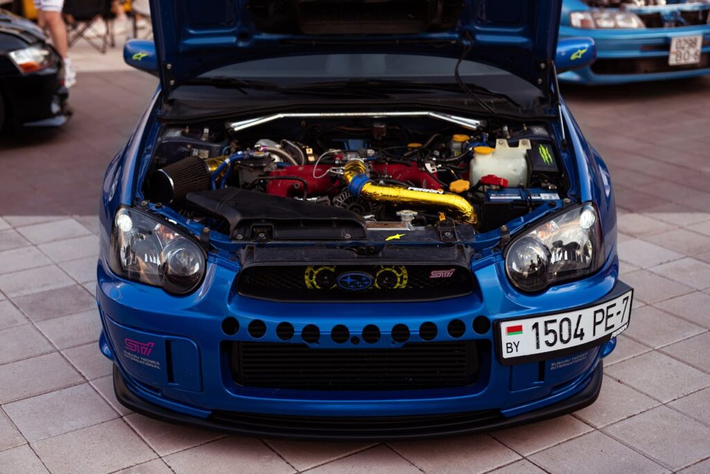Front view of a Subaru Impreza showcasing its engine with an open hood on a paved urban area.