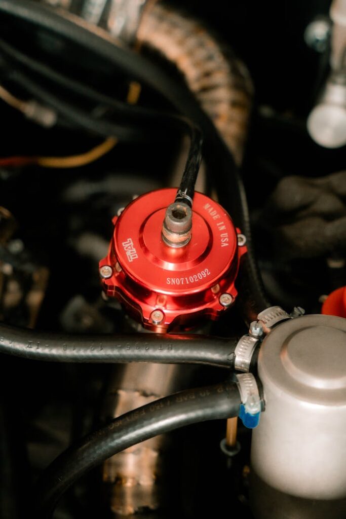 Detailed view of car engine parts showcasing a red valve in an automotive workshop setting.