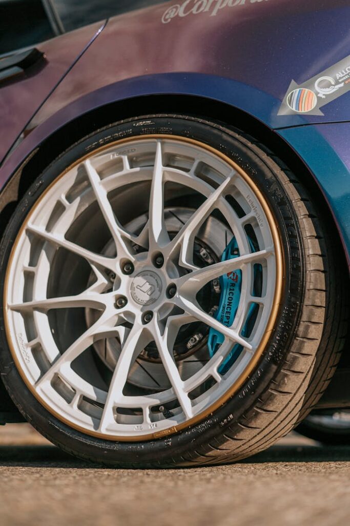 Detailed view of a car's custom alloy rim and tire on pavement.