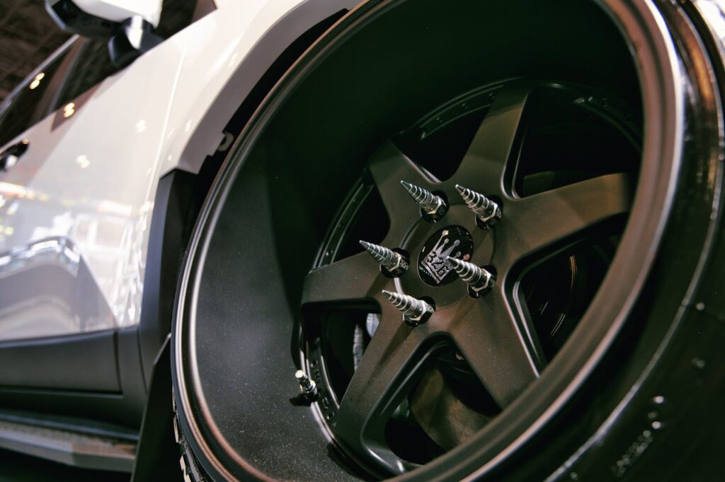 Detailed view of a custom car wheel with spikes at a car show.