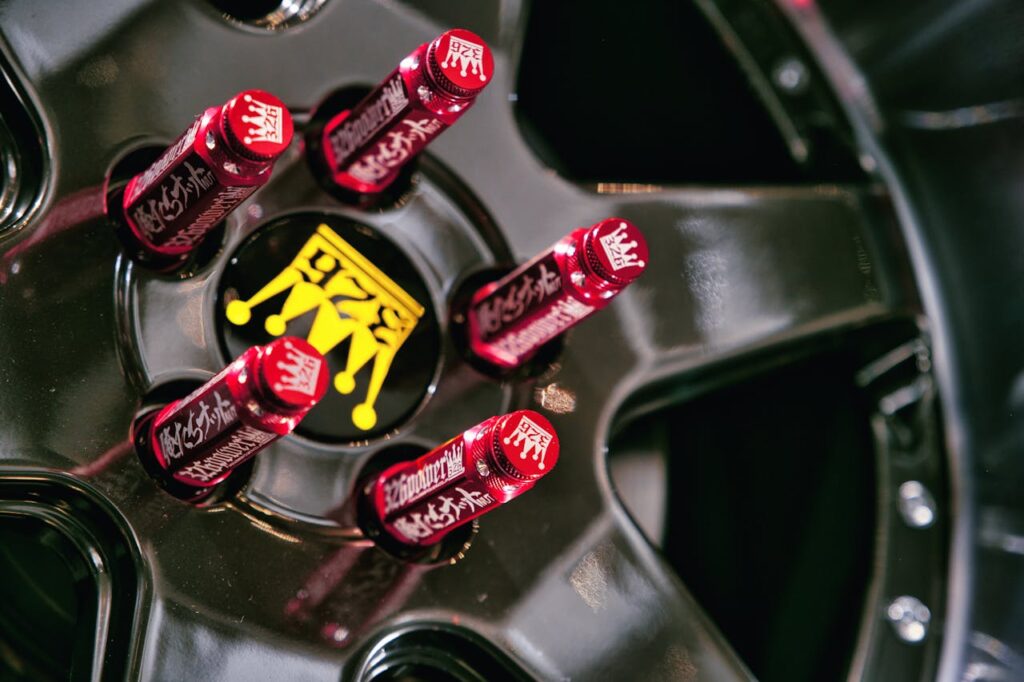 Detailed view of a custom car wheel showcasing red decorative lug caps with Japanese text.