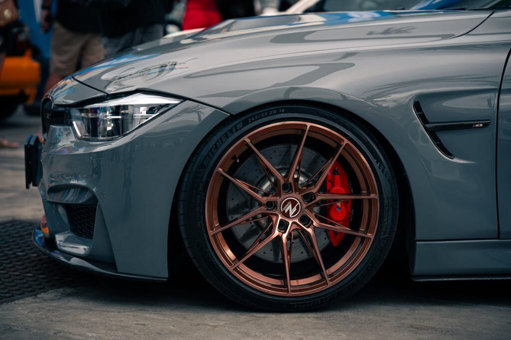 Detailed view of a customized BMW showcasing sleek design and elegant bronze rims at a car show.