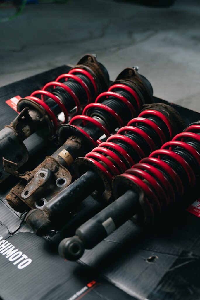 Close-up image of red coilover suspensions with a black background, ideal for automotive or mechanical themes.