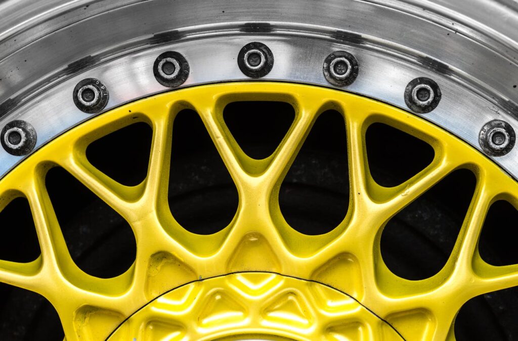 Detailed view of a vibrant yellow aluminum alloy car wheel rim with bolts.
